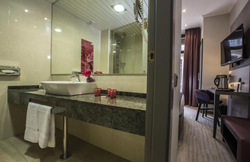 ein Bad mit einem Waschbecken und einem Spiegel in der Unterkunft Leonardo Hotel Barcelona Las Ramblas in Barcelona