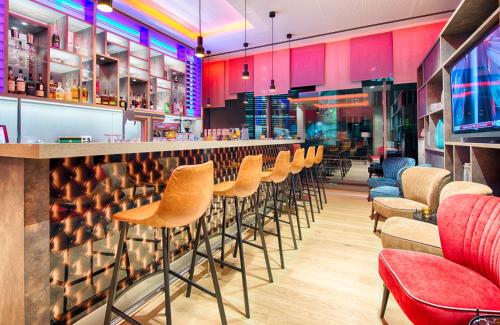 a bar with a row of stools in a restaurant at Leonardo Hotel Munich City South in Munich