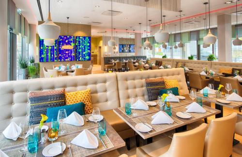 a dining room with tables and chairs in a restaurant at Leonardo Hotel Munich City South in Munich