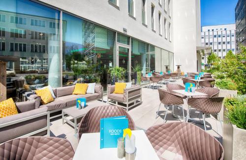 a patio with tables and chairs on a building at Leonardo Hotel Munich City South in Munich