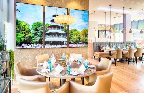 a dining room with tables and chairs and a painting on the wall at Leonardo Hotel Munich City South in Munich