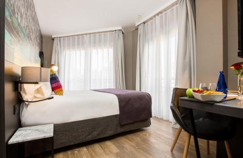 a hotel room with a bed and a desk with a table at Leonardo Boutique Hotel Madrid in Madrid