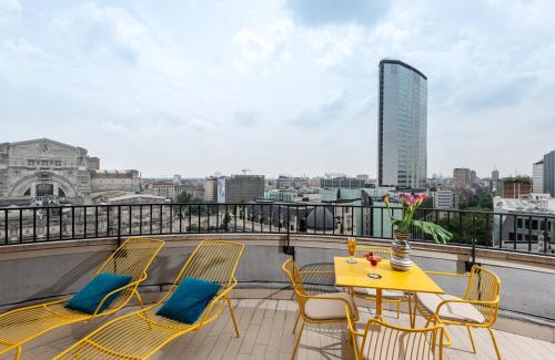 ミラノにあるNYX Hotel Milan by Leonardo Hotelsの黄色のテーブルと椅子、景色を望むバルコニー