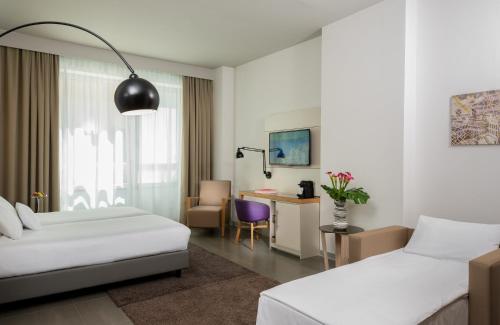 NYX Hotel Milan by Leonardo Hotels في ميلانو: غرفة فندقية بسريرين ومكتب