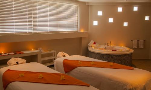 a bathroom with two beds and a tub and a sink at Solana Beach Mauritius - Adults Only in Belle Mare