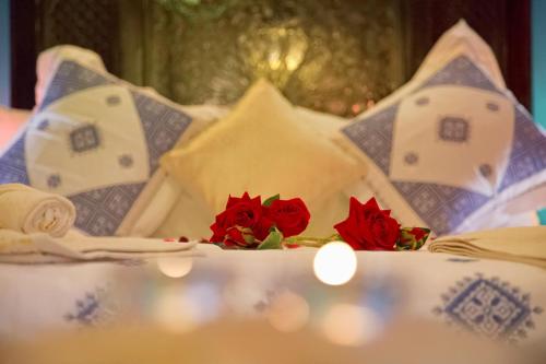 a bed with red roses on top of it at Riad Dar Kassim in Fès