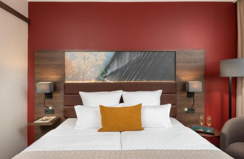 a bedroom with a large bed with a red wall at Leonardo Hotel Bad Kreuznach in Bad Kreuznach