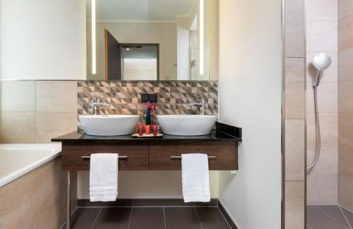 a bathroom with two sinks and a mirror at Leonardo Hotel Bad Kreuznach in Bad Kreuznach