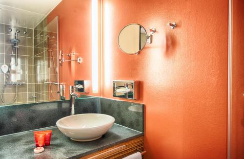 a bathroom with a sink and a mirror at Leonardo Hotel Berlin Mitte in Berlin