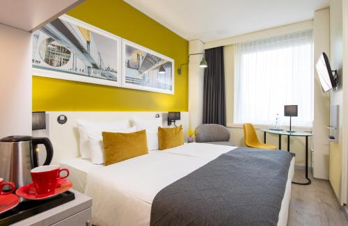 a hotel room with a bed, desk, and television at Leonardo Hotel Berlin Mitte in Berlin
