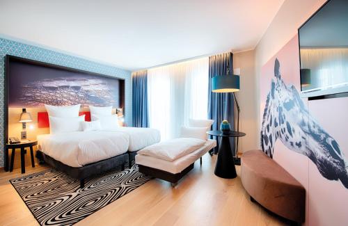 NYX Hotel Munich by Leonardo Hotels في ميونخ: غرفة فندقية بسريرين واريكة