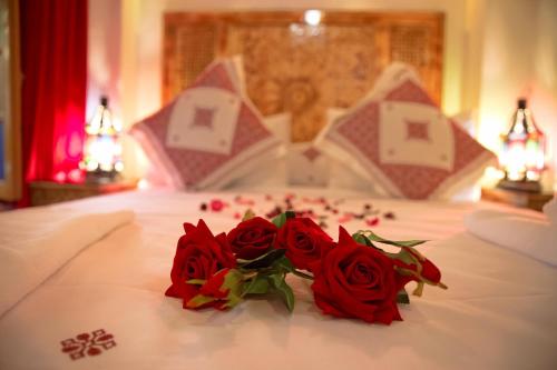 a couple of red roses sitting on a bed at Riad Dar Kassim in Fès