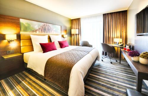 a hotel room with a large bed with red pillows at Leonardo Royal Hotel Ulm in Ulm