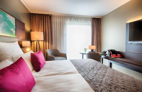 a hotel room with a large bed with pink pillows at Leonardo Royal Hotel Ulm in Ulm