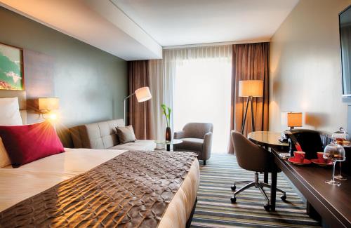 a hotel room with a bed and a desk at Leonardo Royal Hotel Ulm in Ulm