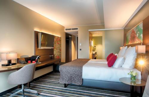 a hotel room with a bed and a desk at Leonardo Royal Hotel Ulm in Ulm