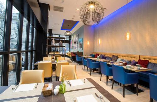 a restaurant with long tables and blue chairs at Leonardo Hotel Madrid City Center in Madrid