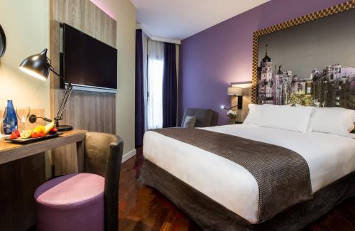 a hotel room with a large bed and a desk at Leonardo Hotel Madrid City Center in Madrid