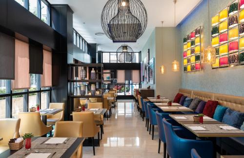 a dining room with tables and chairs and windows at Leonardo Hotel Madrid City Center in Madrid
