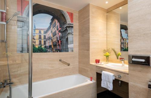 a bathroom with a tub and a sink at Leonardo Hotel Madrid City Center in Madrid
