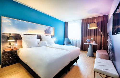 a hotel room with a large bed and a blue wall at NYX Hotel Mannheim by Leonardo Hotels in Mannheim