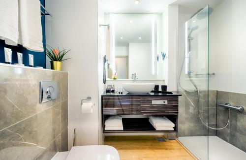 a bathroom with a sink and a shower at NYX Hotel Mannheim by Leonardo Hotels in Mannheim