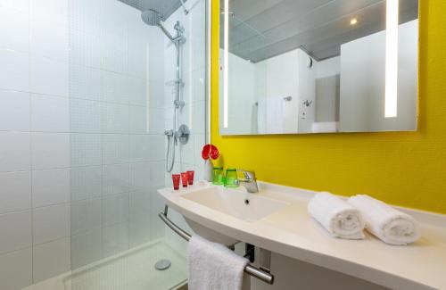 uma casa de banho com um lavatório, um chuveiro e um espelho. em Leonardo Hotel Verona em Verona