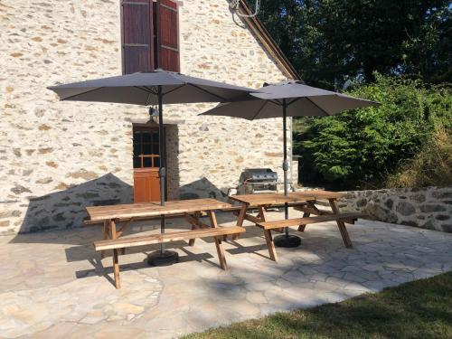 two picnic tables and an umbrella on a patio at le Pargagnat in Préchac
