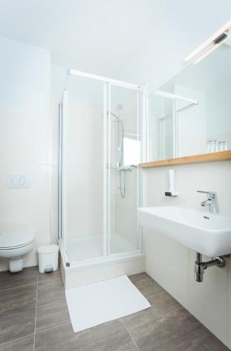 a white bathroom with a shower and a sink at Bauernwirt in Graz