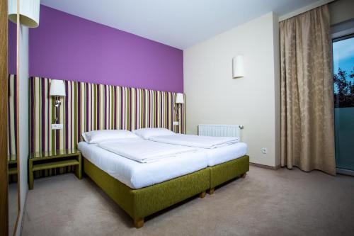 ein Bett in einem Schlafzimmer mit einer lila Wand in der Unterkunft Bauernwirt in Graz