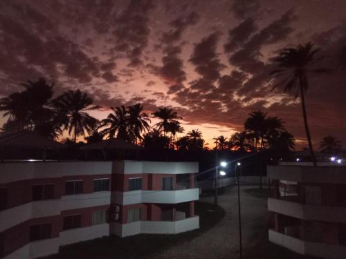 a view of a building at night with palm trees at Apartamento à beira-mar: ideal para famílias . in Ilhéus