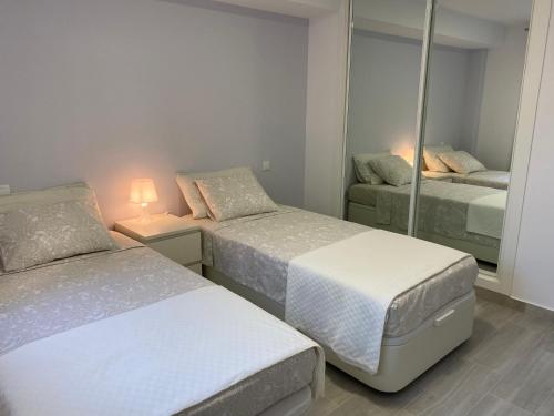 1 dormitorio con 2 camas y espejo en Nice ground floor apartment- 2 bedrooms - 450 meters from the beach, en Cabopino