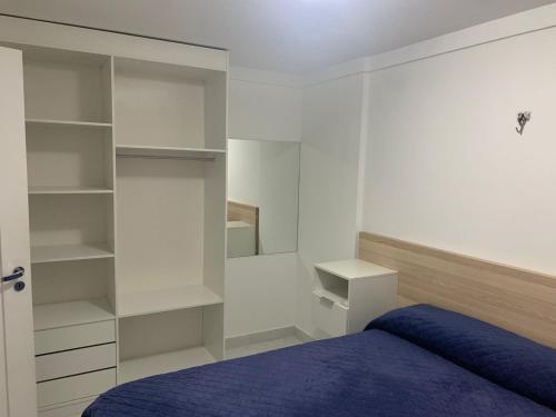 a bedroom with a blue bed and white shelves at Solar Areia Preta 302 in Natal