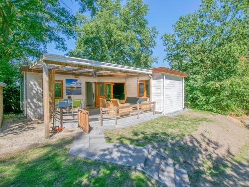 a tiny house with a porch and a deck at Witte Bungalow in Uden