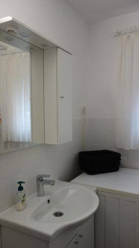 a white bathroom with a sink and a mirror at Apartment Mia in Donja Pačetina