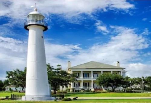 a white lighthouse in front of a house at Biloxi Beach Condo in Biloxi