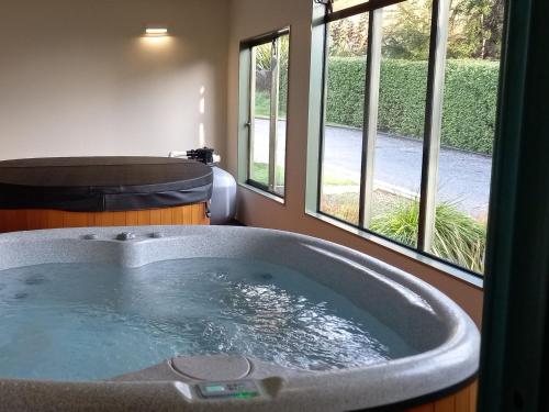 a large bath tub in a room with windows at Wanaka Top 10 Holiday Park in Wanaka