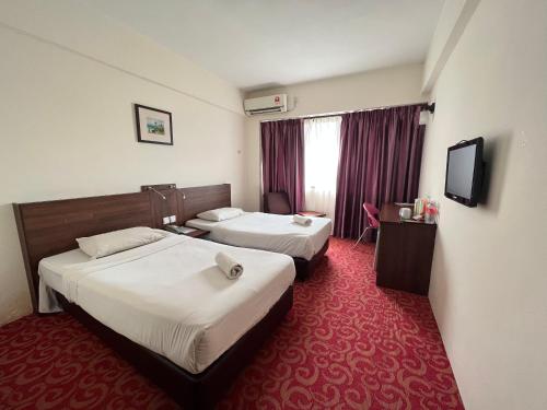 a hotel room with two beds and a flat screen tv at Hotel Yt Midtown Kuala Terengganu in Kuala Terengganu
