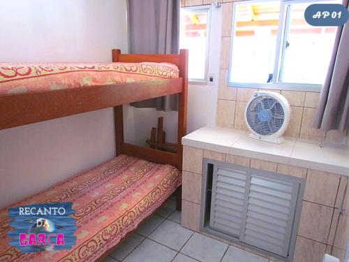 a room with two bunk beds and a fan at Recanto da Garça in Guarda do Embaú