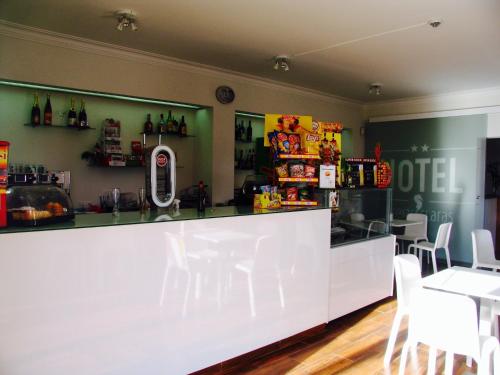 a bar in a restaurant with white chairs and a counter at Hotel Areias Claras in Viana do Castelo