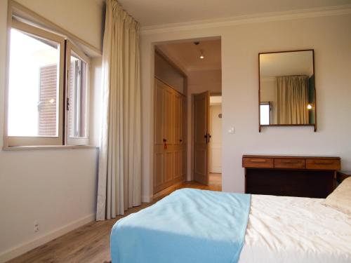 a bedroom with a bed and a mirror and a window at Hotel Areias Claras in Viana do Castelo