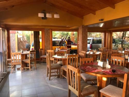a restaurant with wooden tables and chairs and windows at Hotel Corvatsch in San Pedro de Atacama