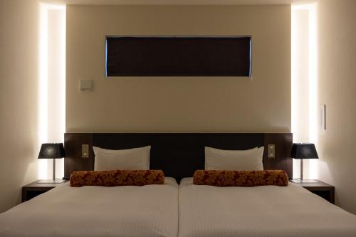 sypialnia z 2 łóżkami i 2 lampami w obiekcie Homm Stay Yumiha Okinawa by Banyan Tree Group w mieście Onna