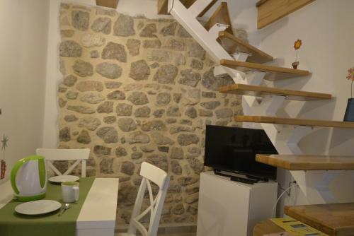 a room with a stone wall with a table and a television at Apartments by the sea Cres - 15171 in Cres