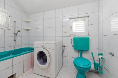 een badkamer met een wasmachine en een blauw toilet bij Apartments by the sea Pisak, Omis - 15177 in Mimice