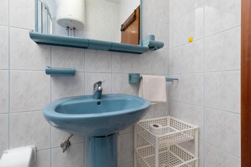 uma casa de banho com um lavatório azul e um espelho. em Apartment Pisak 15177b em Mimice
