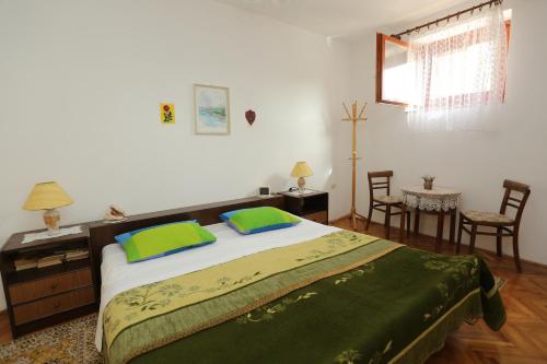 a bedroom with a large bed with two green pillows at Apartments with parking space Splitska, Brac - 15197 in Splitska