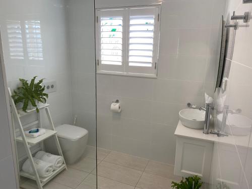 a white bathroom with a toilet and a sink at Rainbow Beach Dream Newly Renovated Stylish One Bedroom Apartment in Rainbow Beach