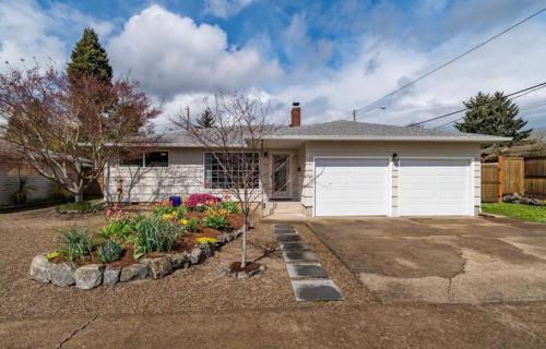 a house with a white garage and some flowers at Colorful 50's Ranch in the Heart of Eugene in Eugene
