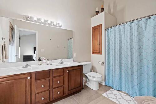 a bathroom with a toilet and a blue shower curtain at Comfortable Townhouse - Short Stroll to Notre Dame in South Bend